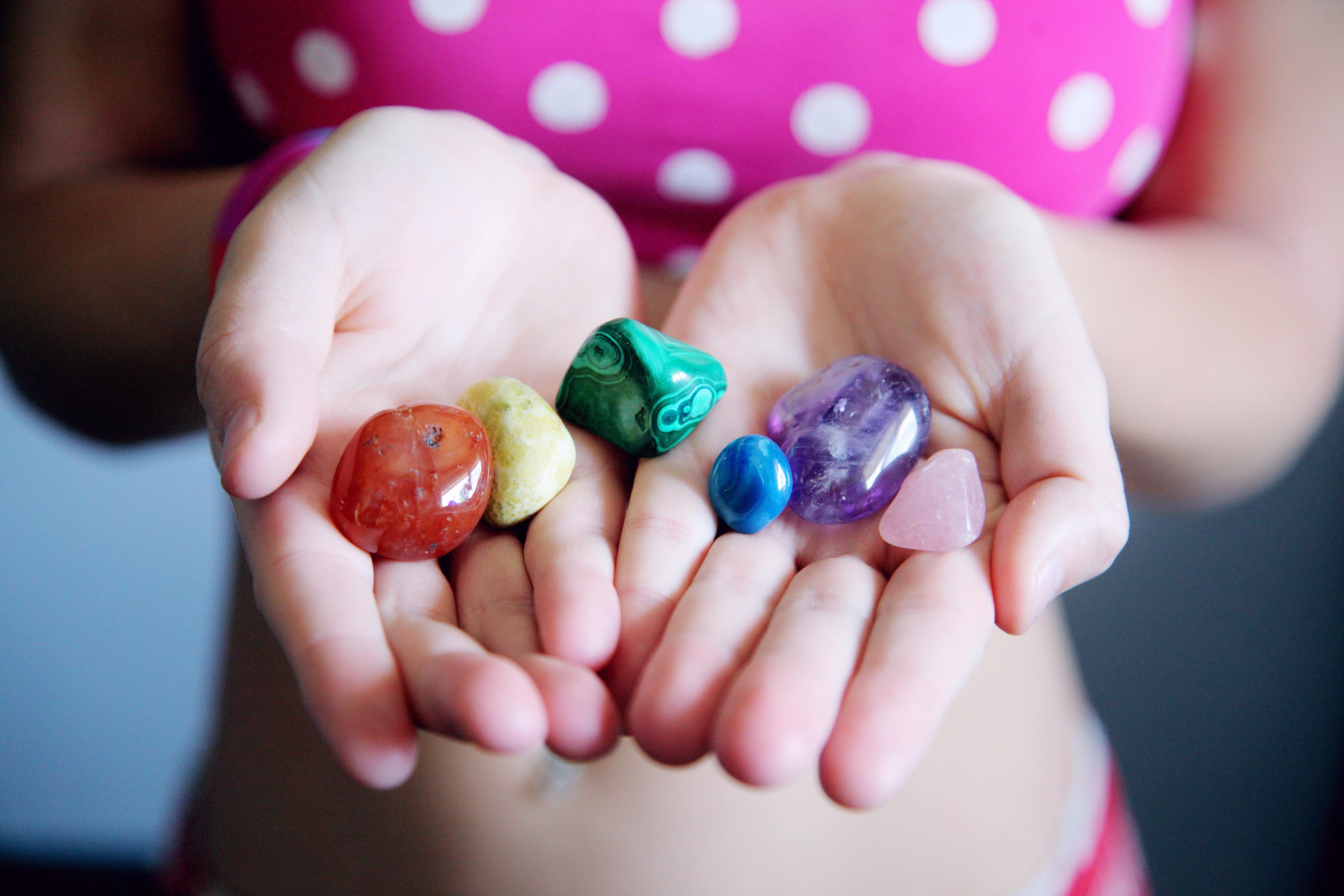 Collection of raw gemstones and polished crystals displayed on shelf for lapidary work